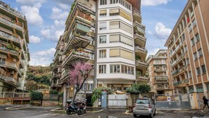 Un edificio residencial de varios pisos con balcones, una entrada con portón y una motocicleta estacionada.