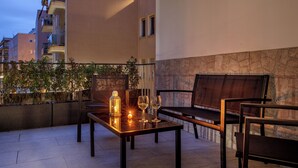 Un área de estar al aire libre con una mesa, sillas y una lámpara de mesa pequeña.