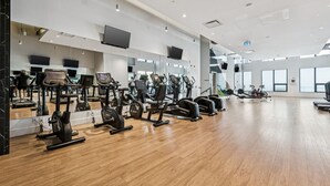 A gym with exercise equipment, mirrors, and large windows. - Elegant 1-Bedroom at BLVD Beltline (Calgary)