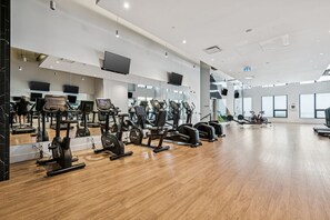 A gym with exercise equipment, mirrors, and large windows. - Elegant 1-Bedroom at BLVD Beltline (Calgary)