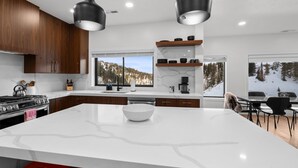 Una cocina moderna con una isla grande, armarios de madera y vistas a un paisaje nevado a través de las ventanas.