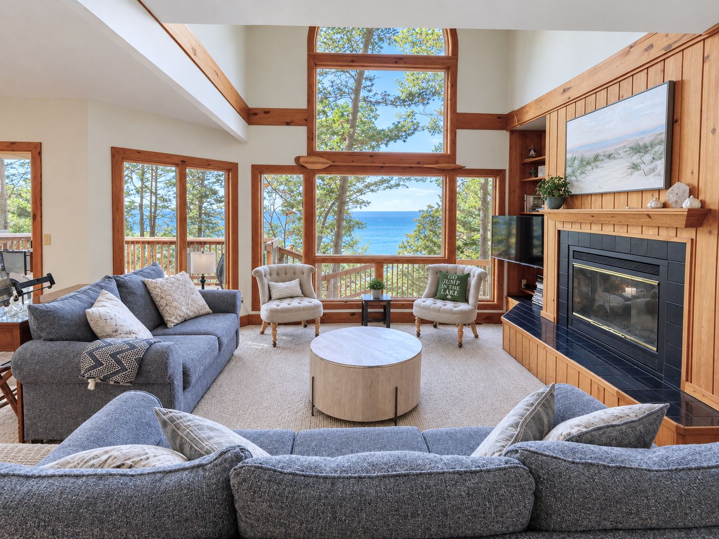 A spacious living room with a fireplace, large windows, and a view of the outdoors.