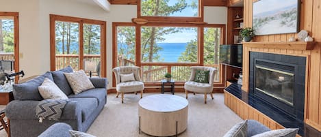 Un salón espacioso con chimenea, ventanas grandes y vistas al exterior.