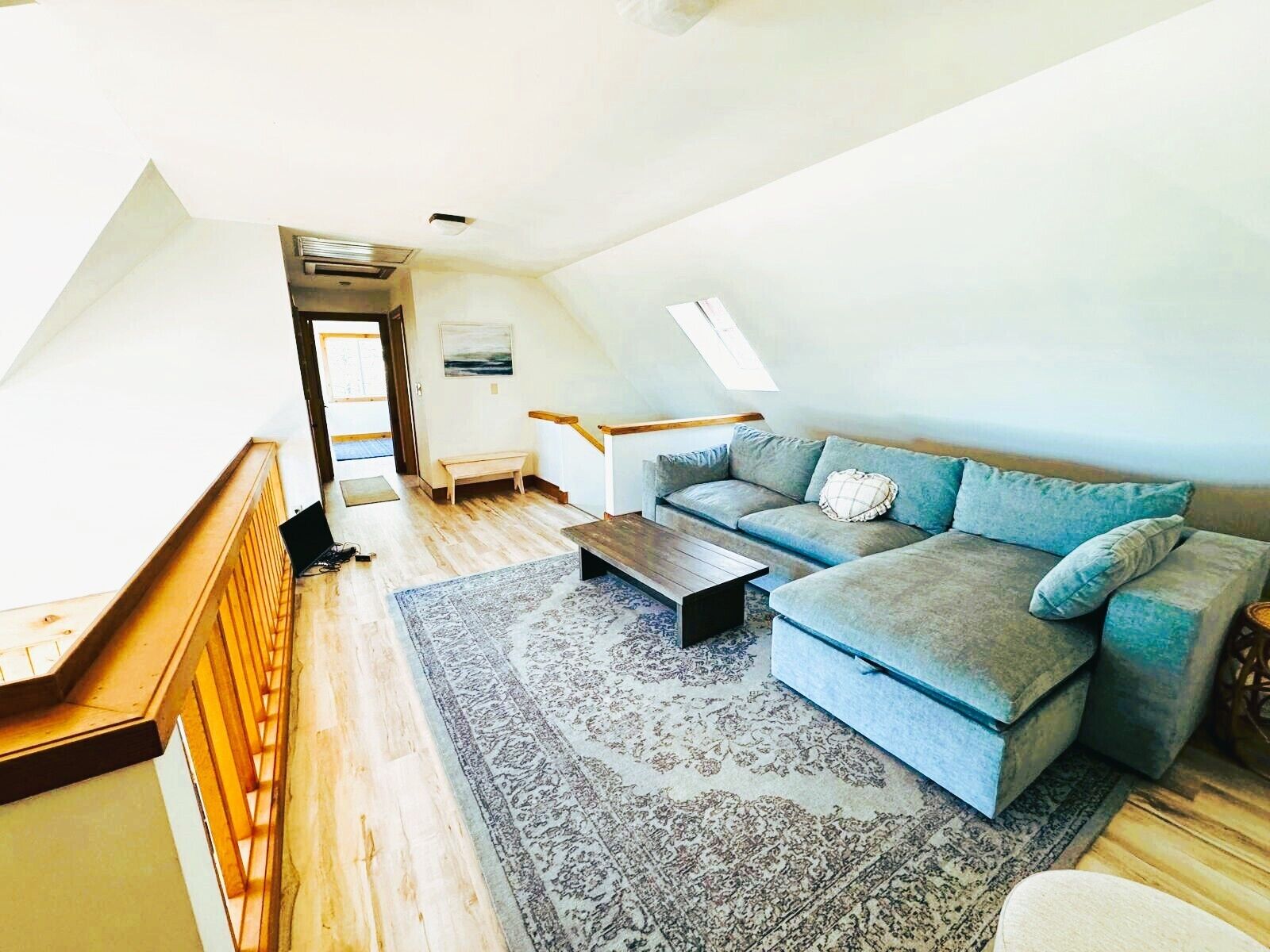 A loft-style room with a blue sofa, a wooden coffee table, and a patterned rug.