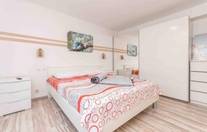 Ein modernes Schlafzimmer mit Bett, Nachttischen, einem Kleiderschrank und Kunstwerken an den Wänden.