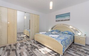 Un dormitorio con cama, armario, mesita de noche y un cuadro en la pared.