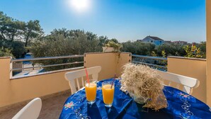 A balcony with a table set for two, two glasses of orange juice, and a white chair.