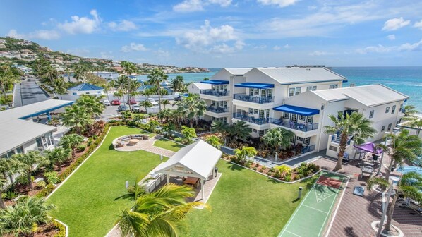 A resort with multiple-story buildings, a pool area, and a view of the ocean. - Ocean-View Studio at Flamingo Beach – Beachfront St. Maarten Escape (Philipsburg)