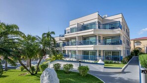 A multi-story hotel with balconies, a paved driveway, and palm trees. - Ocean-View Studio at Flamingo Beach – Beachfront St. Maarten Escape (Philipsburg)