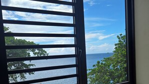 A wooden table with a view of the sea through a window with horizontal blinds.