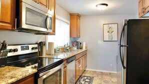 A kitchen with wooden cabinets, stainless steel appliances, a granite countertop, and a backsplash.