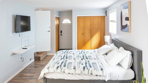 A bedroom with a bed, a TV, a wardrobe, and a door.