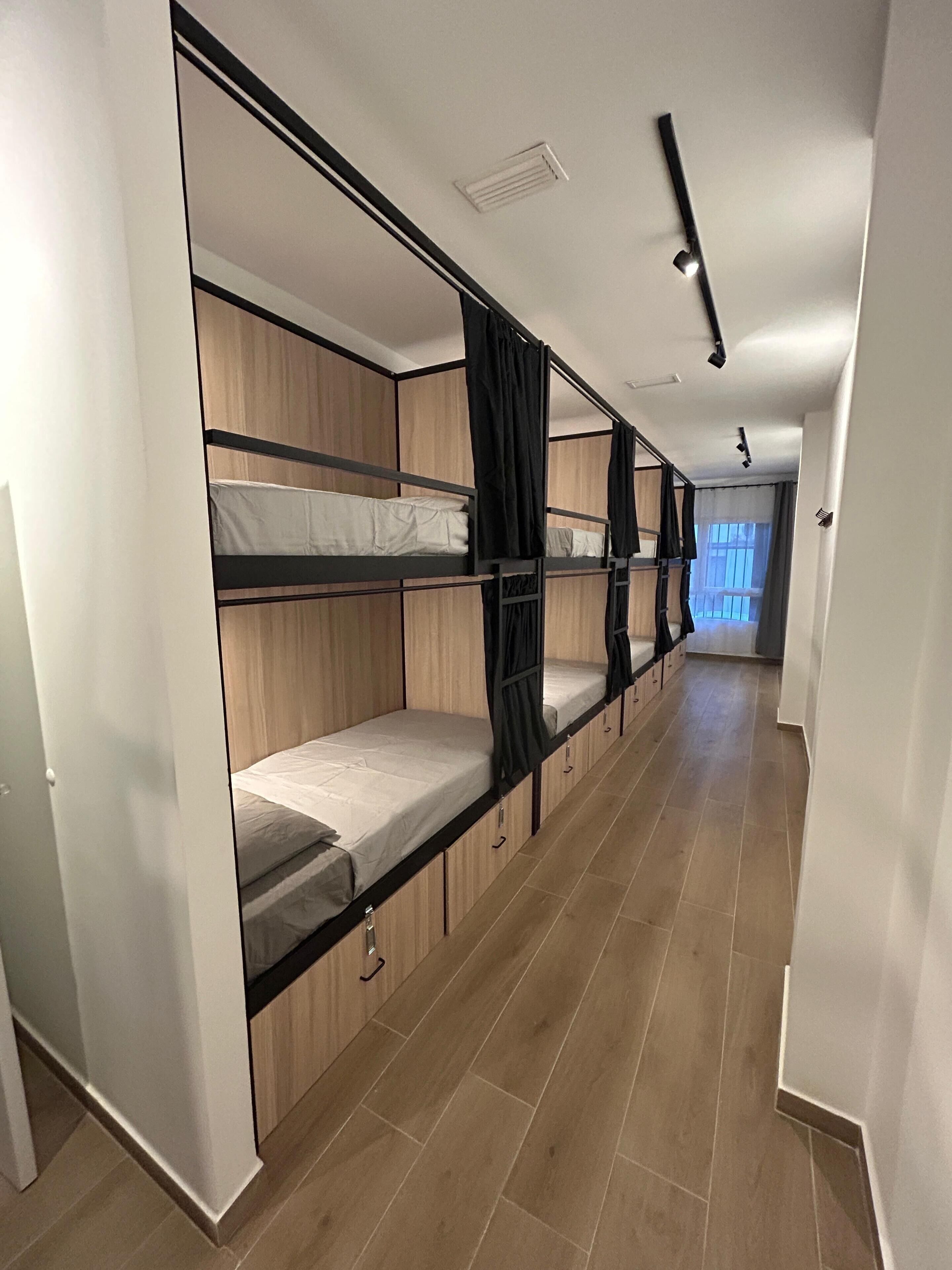 A corridor with bunk beds, wooden paneling, and a tiled floor.