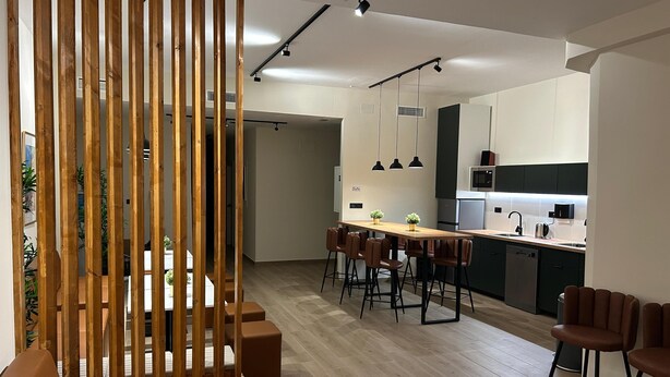 A modern kitchen with a dining area, wooden partition, and bar stools. - ALMA one (Alicante)