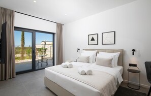 Une chambre d’hôtel avec un grand lit, un balcon avec vue et deux tableaux encadrés au mur.