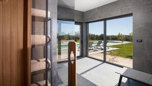 A modern interior with a glass door leading to a pool area, a wooden staircase, and a view of the outdoors. - Cozy home in Bale with sauna (Bale)