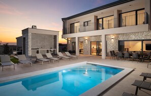 A modern two-story house with a swimming pool, outdoor seating, and a stone facade. - Nice home in Bale with sauna (Bale)