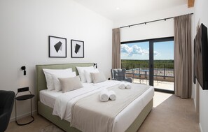 A hotel room with a large bed, a chair, a small table, and a balcony with a view. - Nice home in Bale with sauna (Bale)