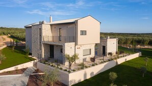 Een modern herenhuis met twee verdiepingen, een stenen gevel, een balkon en een verzorgde tuin.