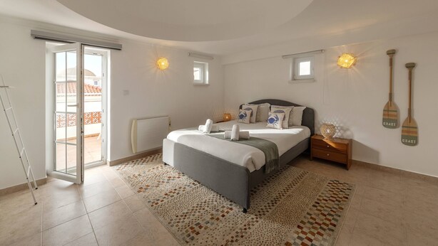 A bedroom with a bed, bedside tables, a window, and a view of the outside. - Second Life Baleal - 350 meters to the sea (Peniche)