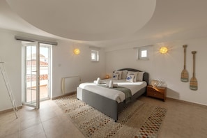 Een slaapkamer met een bed, nachtkastjes, een raam en uitzicht op het omliggende landschap.