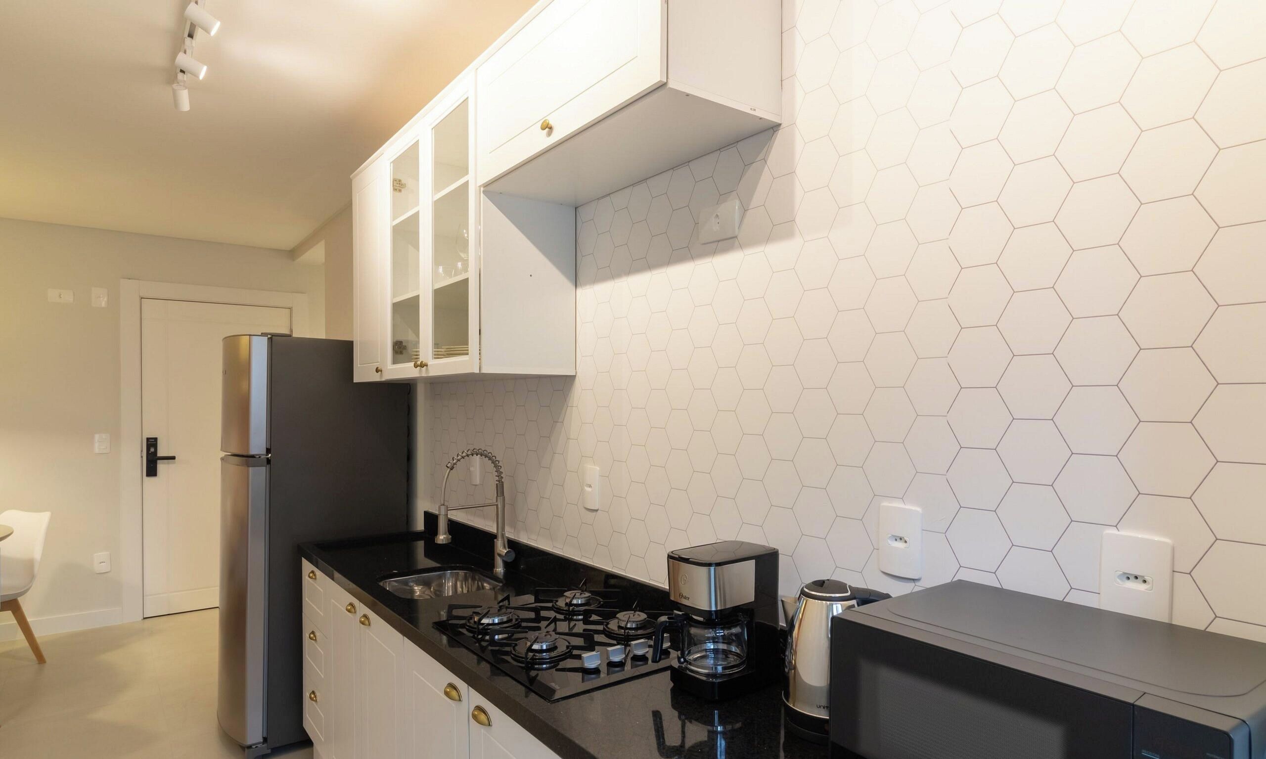 A compact kitchen with white cabinets, a gas stove, a coffee maker, and a microwave.