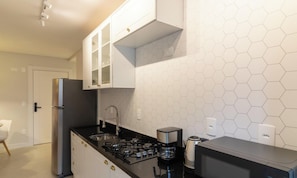 A compact kitchen with white cabinets, a gas stove, a coffee maker, and a microwave. - Apt With BBQ 450m From the Beach Evu1802 (Itapema)