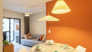 A modern living room with a grey sofa, a dining table set with plates, cups, and cutlery, and two pendant lights. - Apt With BBQ 450m From the Beach Evu1802 (Itapema)