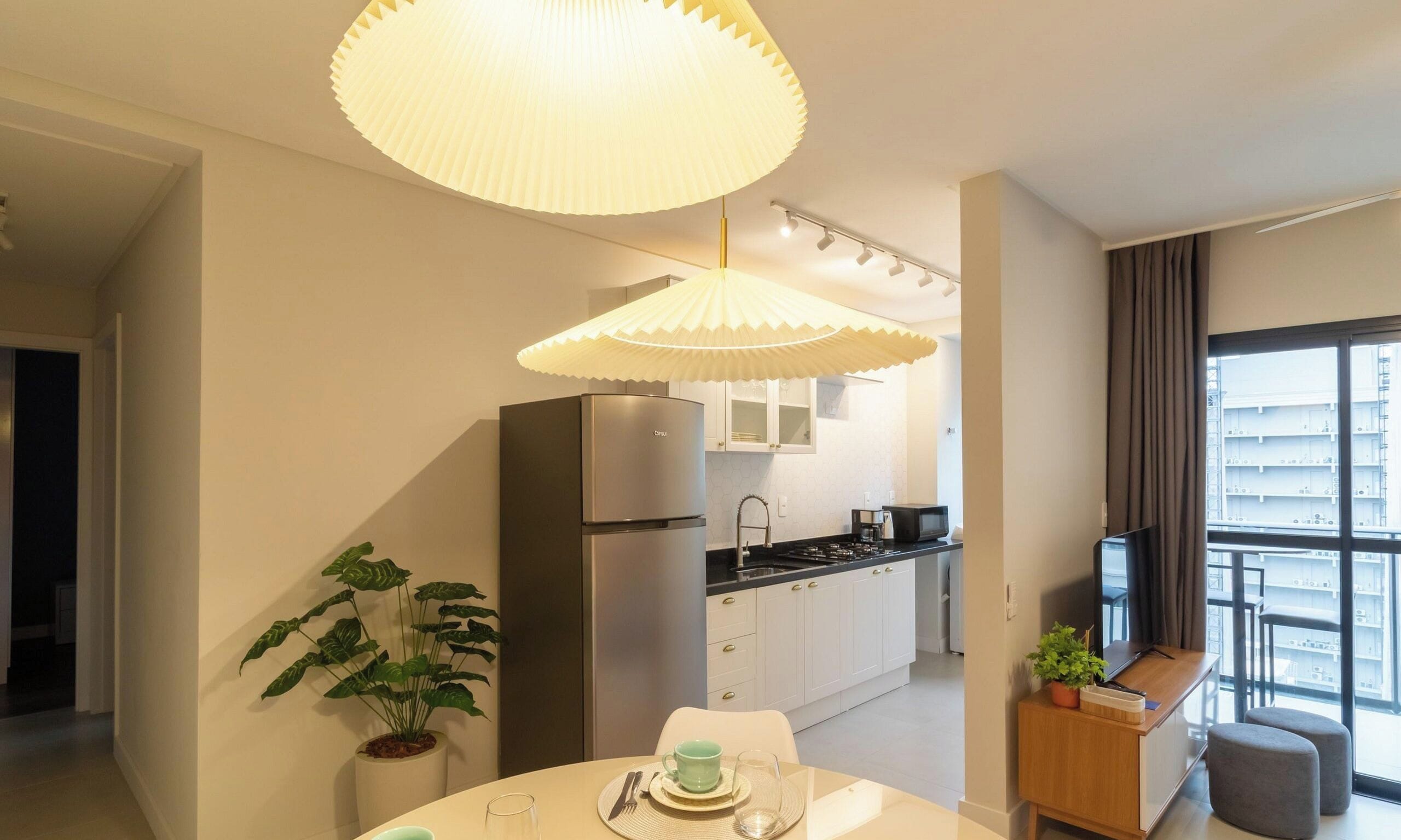 Una cocina moderna con refrigerador, estufa y comedor con una mesa para dos.