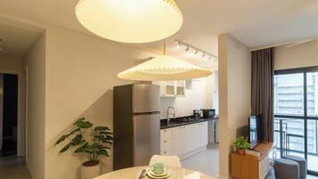 Una cocina moderna con refrigerador, estufa y comedor con una mesa para dos.