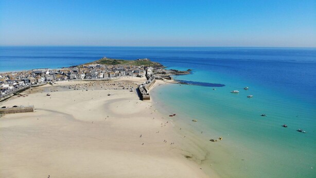 An aerial view of a coastal town with a sandy beach, a fortified structure, and clear blue waters. - Traditional Cornish Cottage & Garden, Redruth (Redruth)