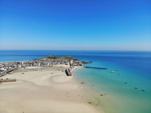 An aerial view of a coastal town with a sandy beach, a fortified structure, and clear blue waters. - Traditional Cornish Cottage & Garden, Redruth (Redruth)
