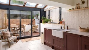 A modern kitchen with a large sliding glass door leading to an outdoor patio area. - Traditional Cornish Cottage & Garden, Redruth (Redruth)