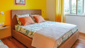 A bed with a floral bedspread, two orange pillows, and a quilted blanket. - 1 bedroom gorgeous apartment in Brsec (Brsec)