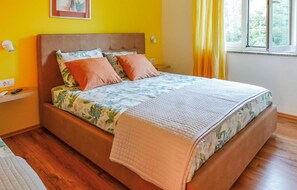 A bed with a floral bedspread, two orange pillows, and a quilted blanket. - 1 bedroom gorgeous apartment in Brsec (Brsec)