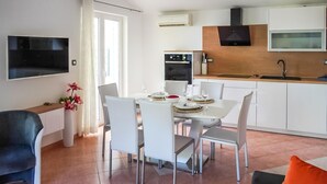 A modern kitchen with white cabinets, a black stove, and a wooden countertop. - 1 bedroom gorgeous apartment in Brsec (Brsec)