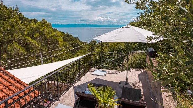 A balcony with a view of the sea, a white umbrella, and a small table with a chair. - 1 bedroom gorgeous apartment in Brsec (Brsec)