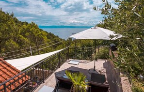 A balcony with a view of the sea, a white umbrella, and a small table with a chair. - 1 bedroom gorgeous apartment in Brsec (Brsec)