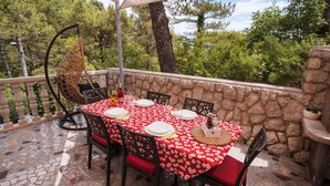 An outdoor dining area with a stone wall, a tiled floor, and a table set for four with red and white tablecloths. - Lovely apartment in Brsec with WiFi (Brsec)