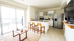Een modern appartement met keuken, eethoek en een grote glazen schuifdeur naar een balkon.