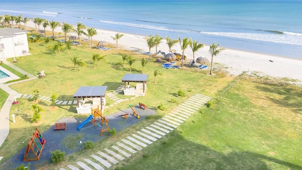 A beachside resort with a playground, palm trees, and a view of the ocean. - Pacific Breeze -V5-5D- 2 bed, 2 bath (Punta Chame)