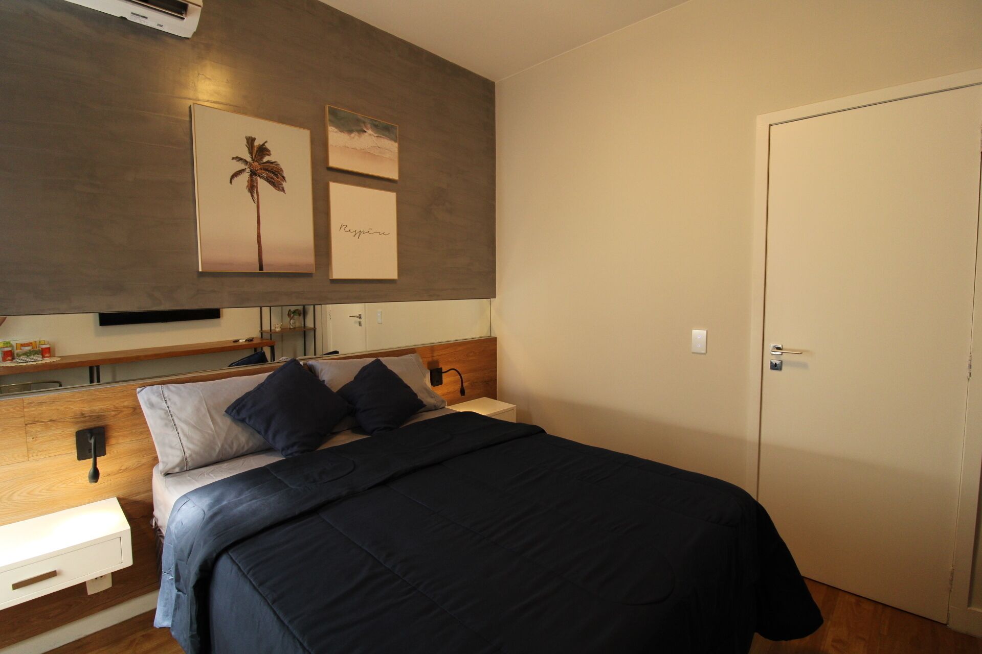 A bedroom with a bed, bedside tables, a wardrobe, and wall art.