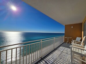 Ein Balkon mit Meerblick, einem weißen Geländer und einem kleinen Tisch mit Stühlen.