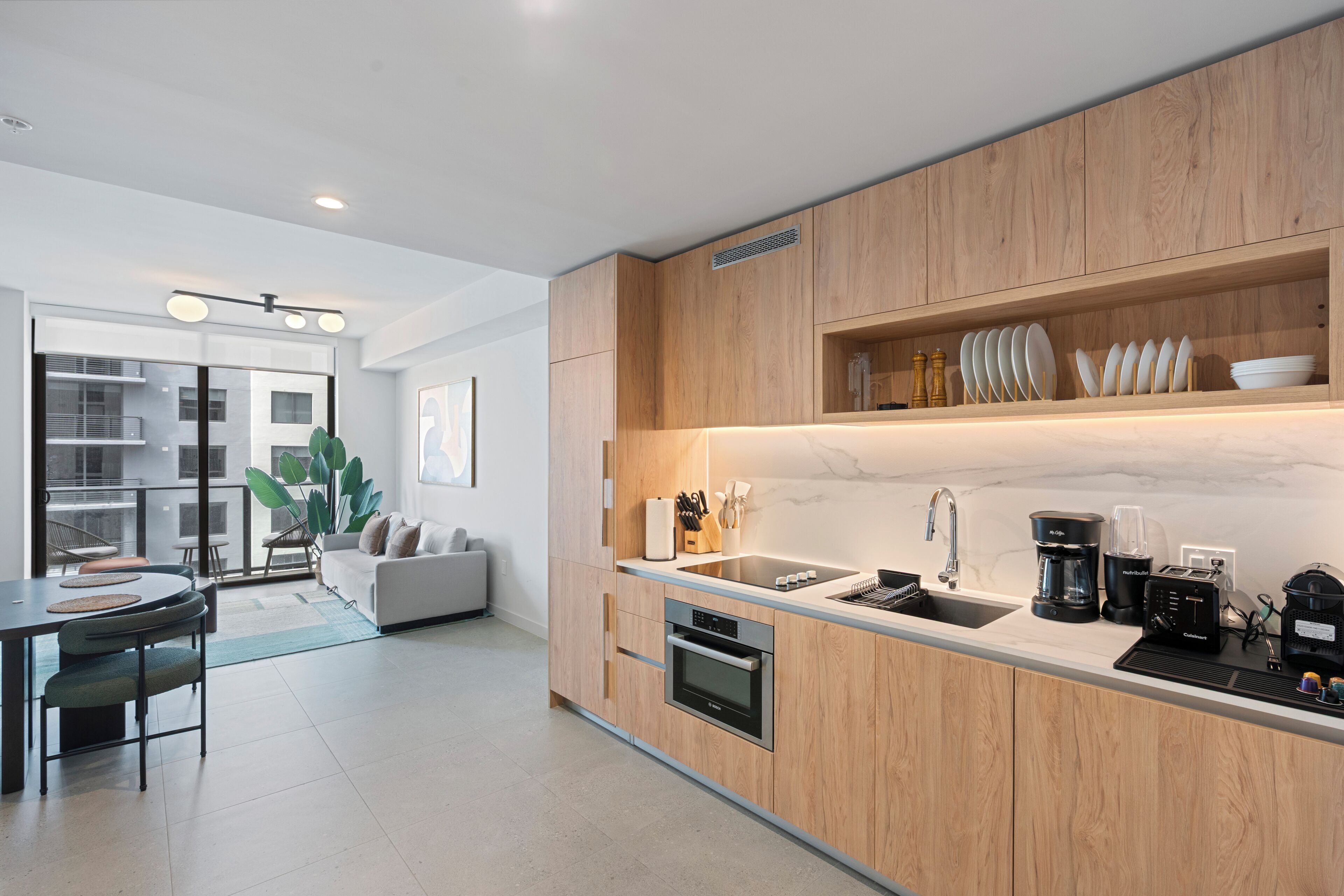 Una cucina moderna con mobili in legno, forno integrato, lavandino e zona pranzo con tavolo e sedie.