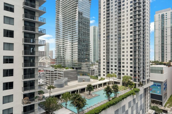 Un edificio residencial alto con varios balcones, una piscina en la azotea y zonas verdes circundantes.