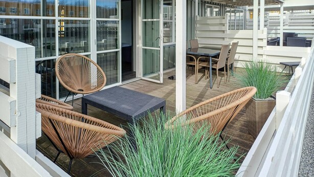 Un balcon agrémenté de meubles en osier, d’une table et de plantes en pot.