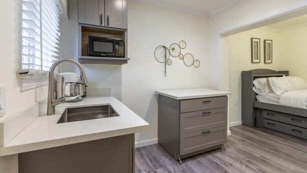 A compact kitchen with a sink, microwave, and cabinets. - Marbella Lane - Adorable and Quiet Studio (San Mateo)
