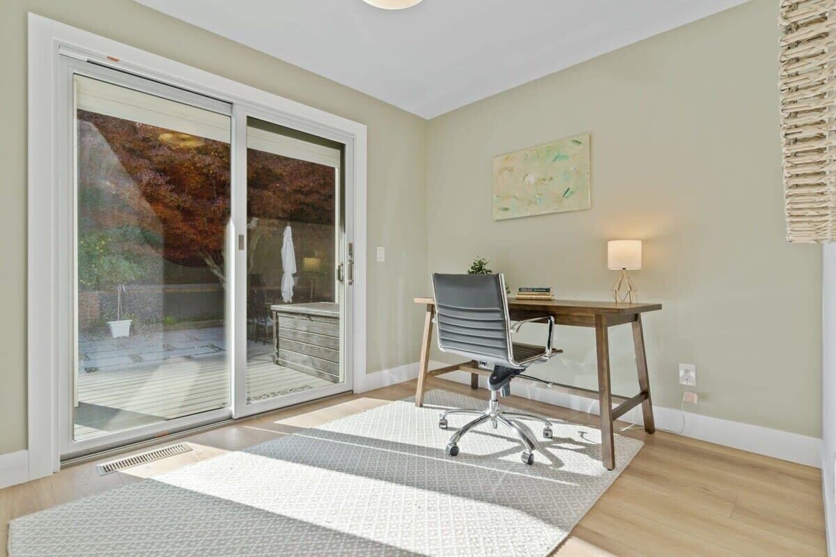 A room with a desk, chair, and a sliding glass door leading to a patio.