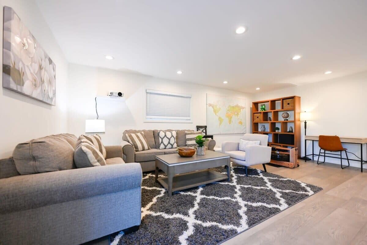 Una sala de estar moderna con un sofá gris, sillones blancos, una mesa de centro y un mapa mundial en la pared.