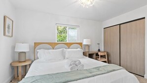 A neatly arranged bedroom with a large bed, two bedside tables, a window, and a wardrobe. - Marbella Lane - Modern 3BROasis in SiliconValley (San Jose)